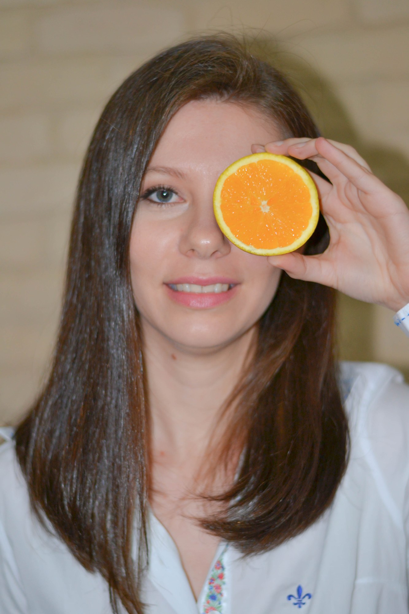 Nutricionista Rosiene Badaró segurando meia laranja em frente ao rosto